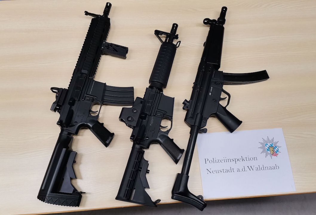 Jugendliche spielen mit Softair-Gewehren auf Wiese