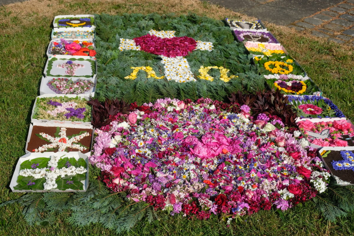 Blumenteppiche zu Fronleichnam mit blütenbestückten Pizzaschachteln