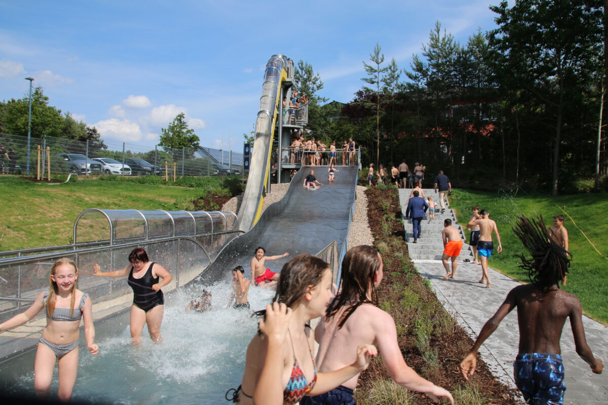 Glückliche Kindergesichter freuen sich über neue Wasserrutsche